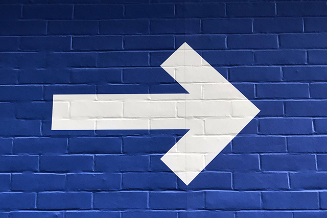 White arrow painted on a blue brick wall