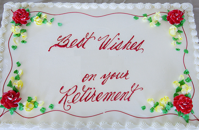 picture of a square white frosted cake, with flowers at the corner and Best Wishes in your Retirement written in red frosting
