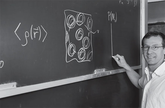 Professor Phillip Geissler writing an equation in chalk on a blackboard