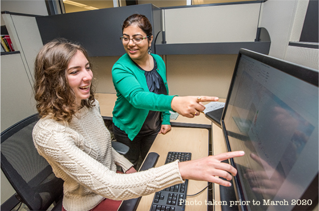 an intern and mentor look at a computer screen