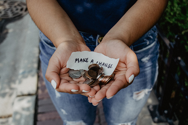 hands holding coins and note saying make a change