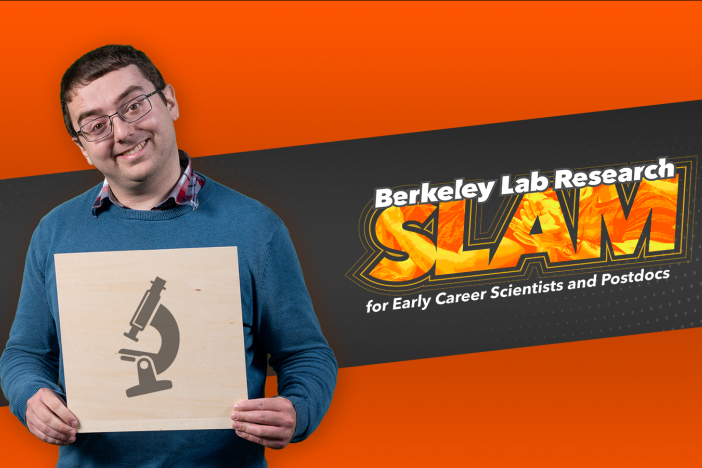 Researcher Alexander Pattinson holds an illustration of a microscope while standing in front of the Berkeley Lab Research SLAM logo
