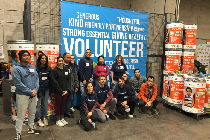 Volunteers stand in front of a food bank of contra costa and solano banner