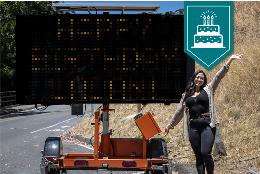 Ladan Khandel in front of birthday sign with banner icon