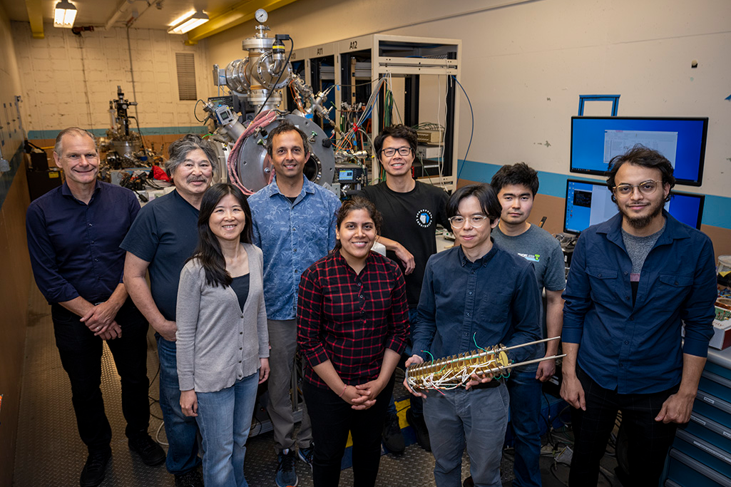 Members of the team that conducted the research. Theory lead Liang Tan is holding one of the ion accelerators used to form quantum light emitters in silicon. (Left to right: Thomas Schenkel, Takeshi Katayanagi, Qing Ji, Arun Persaud, Kaushalya Jhuria, Wei Liu, Liang Tan, Yertay Zhiyenbayev, and Walid Redjem).