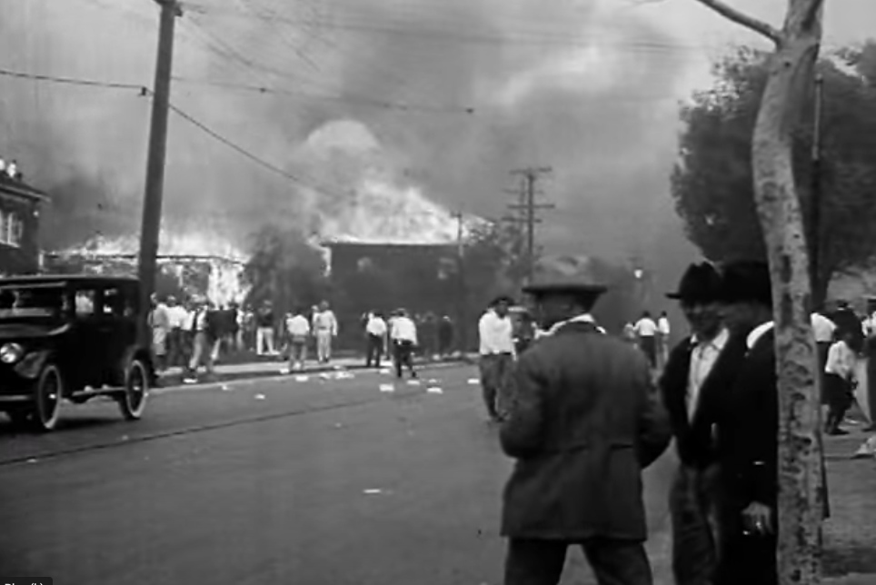 buildings burning with people in foreground watching