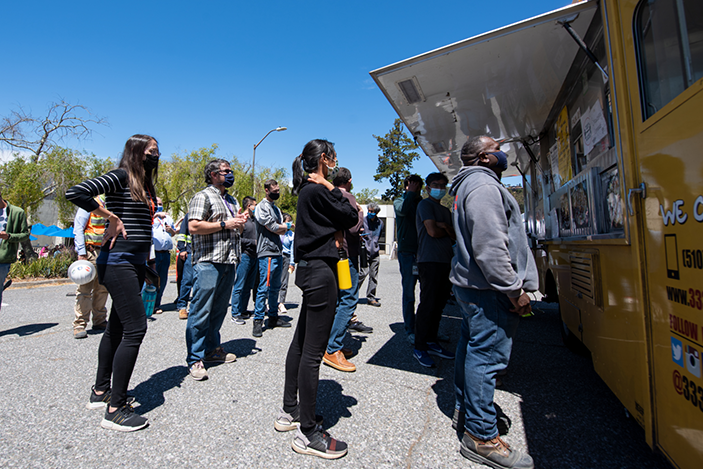 people stand in line to order at a food truck