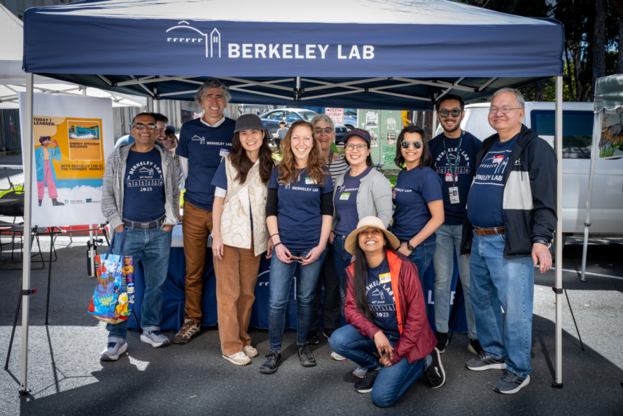 A group of Berkeley Lab volunteers from the Early Career Employee Resource Group stand in front of the Lab booth at the Berkeley Farmers market