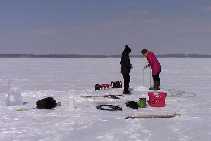 Two people standing in ice field performing experiment