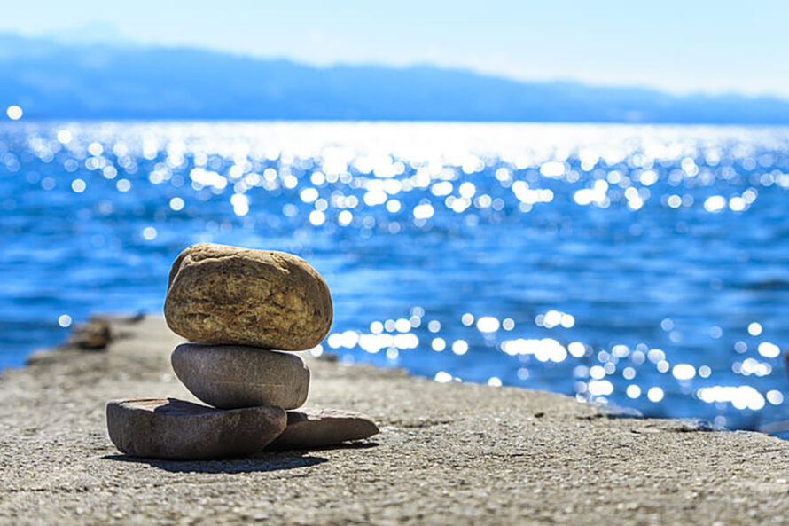 three rocks balancing on top of one another with water in the background