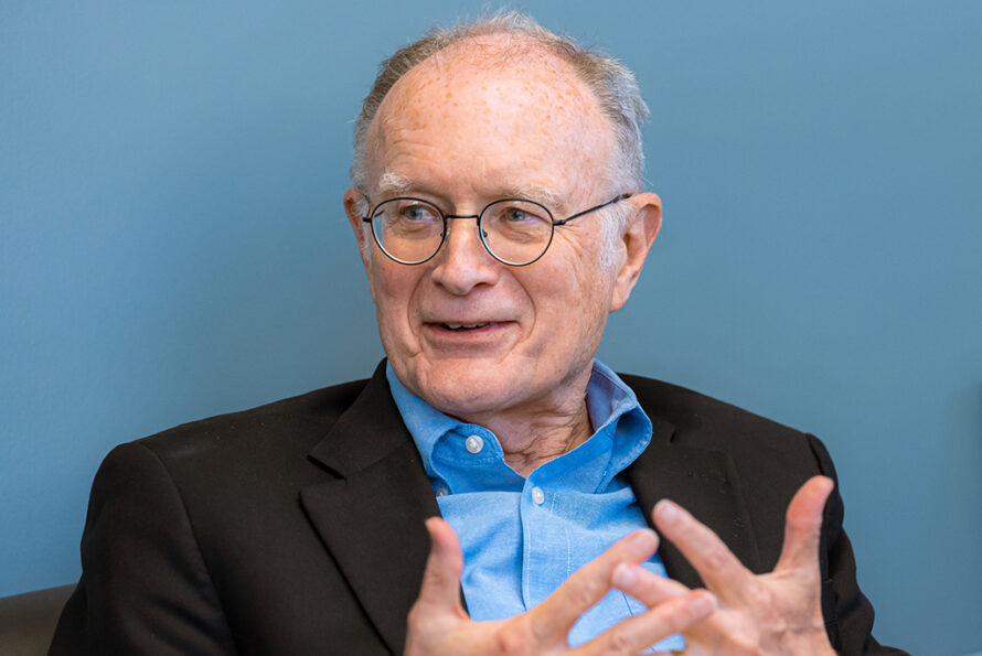 Peron wearing light blue shirt with dark suit jacket using his hands as he talks