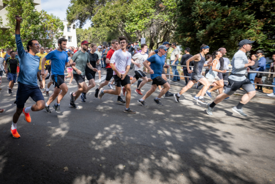 A group of runners running on a paved road past the camera