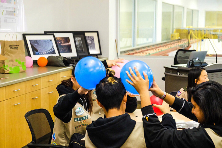 Group of young people experimenting with static electricity by rubbing balloons on their heads