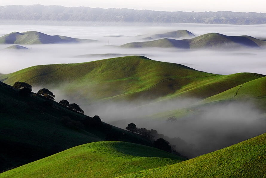 Rolling green hills with wispy clouds in the sky