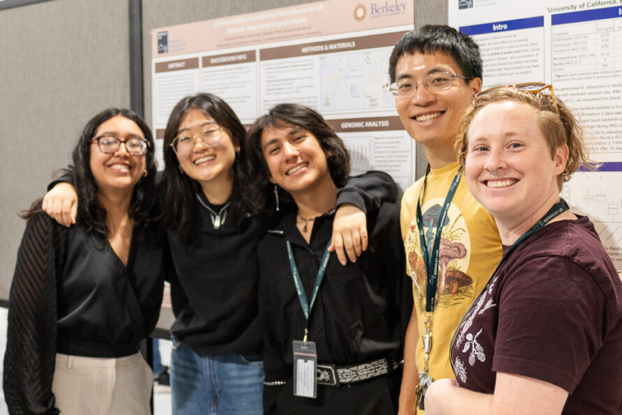 Group of five young people in front of a presentation poster