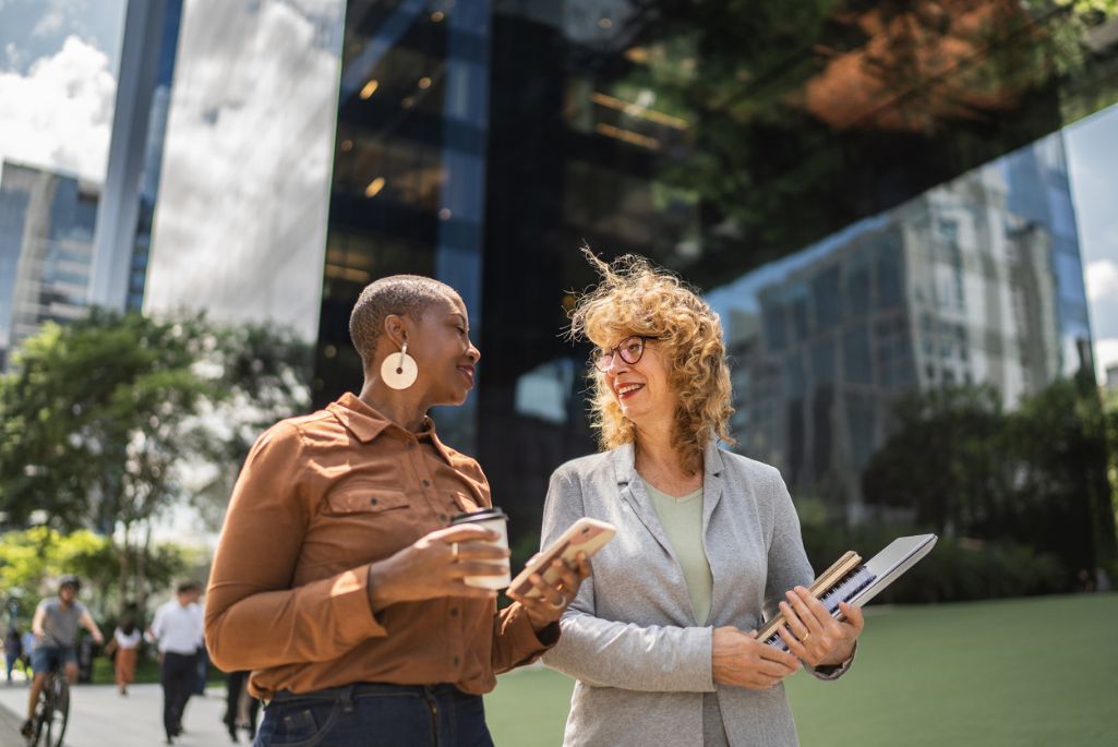 Two people engaged in conversation outside a modern office building.