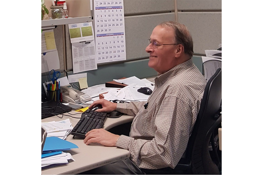 Photo of smiling person sitting at desk using computer keyboard