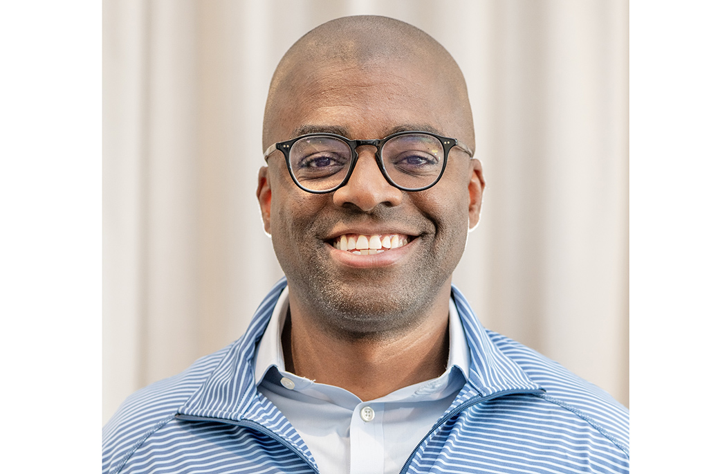 Person wearing blue shirts with glasses smiling into camera