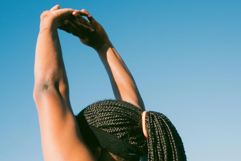 Headshot of person with arms stretched over their head