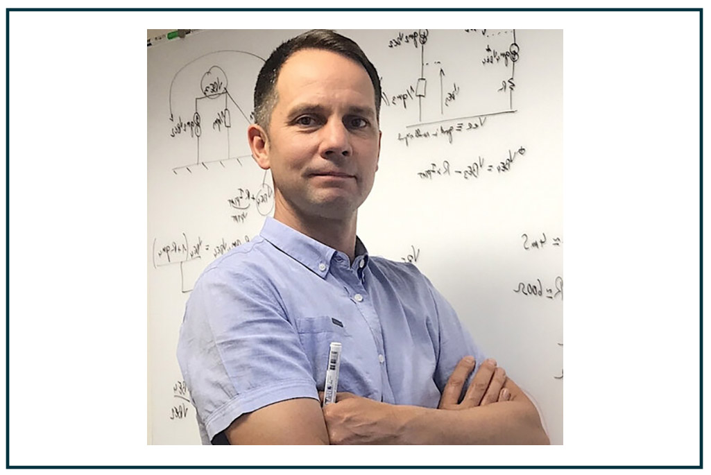 Person wearing blue shirt standing in front of white board covered with mathematical formulas.