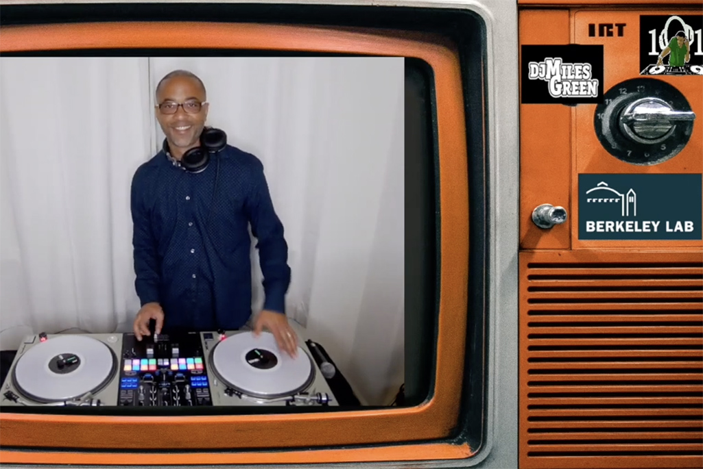 Person standing behind a music turntable with hand on one turntable.