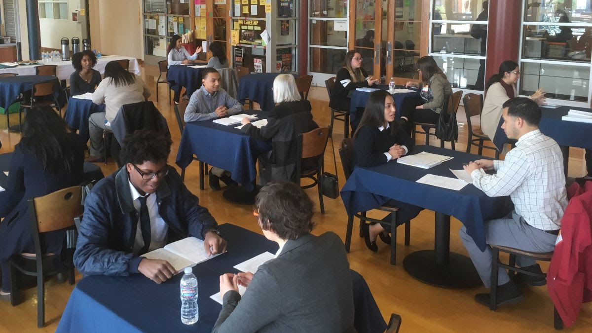 Pairs of persons sitting across from one another performing mock interviews.