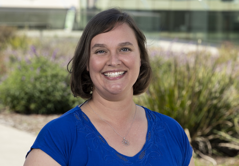 Headshot of person outside with plants in background.