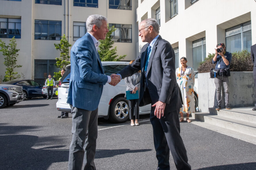 Two persons standing outside shaking hands in greeting.