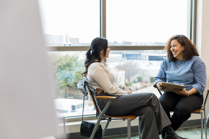 Two women seated by windows having a conversation