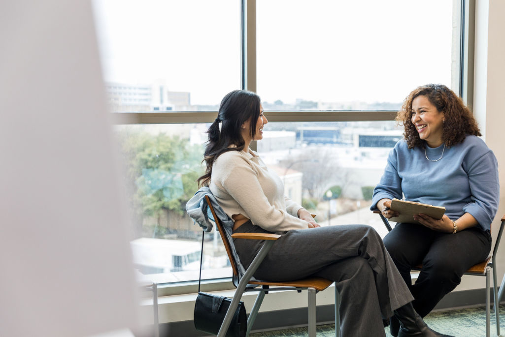 Two women seated by windows having a conversation