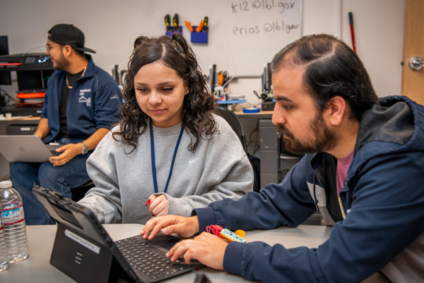 One person typing on laptop computer with second person looking on.