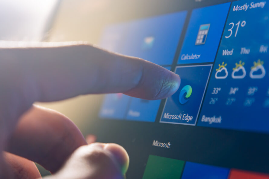 Person's finger touching a computer monitor displaying Windows operating system.
