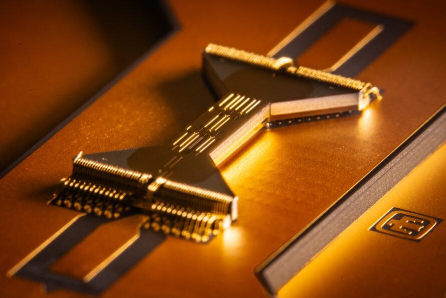 Closeup of gold, hour-glass shaped chip used to trap ions