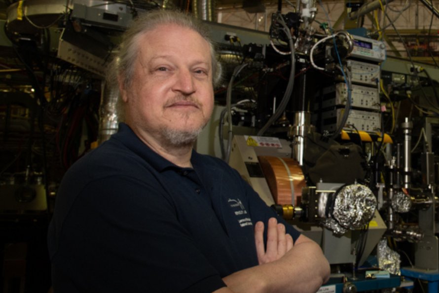 Person in lab environment sitting at table with arms crossed.