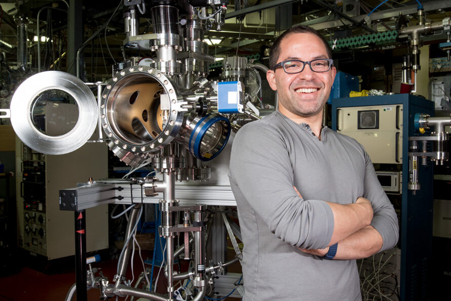 Person wearing light gray shirt standing in front of scientific equipment