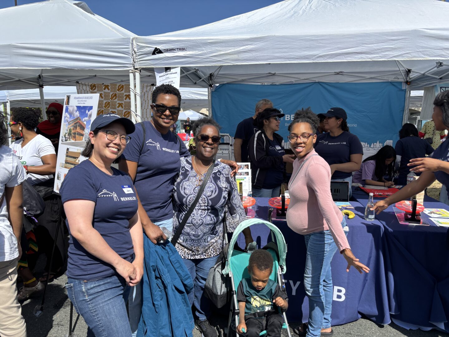 Gathering of persons wearing Berkeley Lab logo t-shirts standing in front of booth.