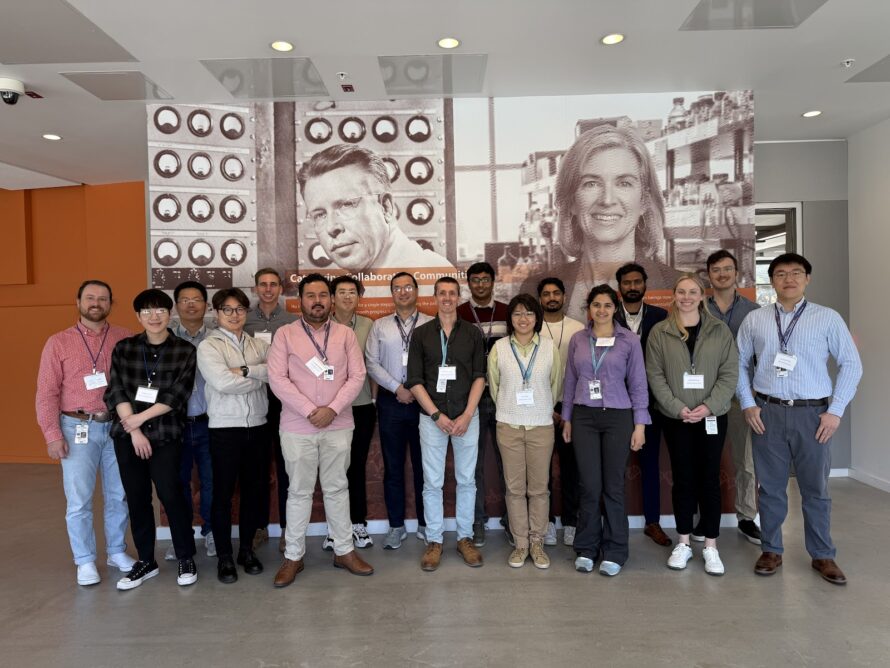 Large gathering of persons standing in front of panels with images of two persons.