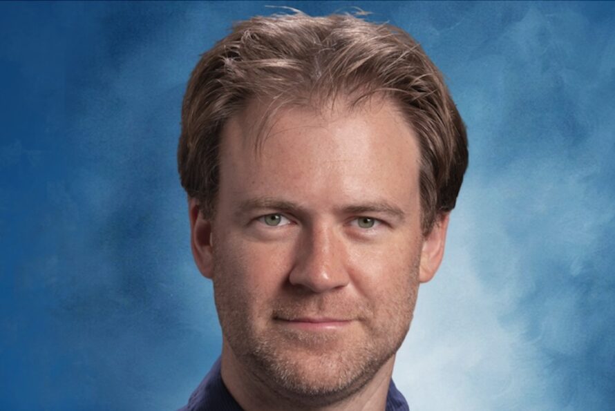 Headshot of person set off with blue background.