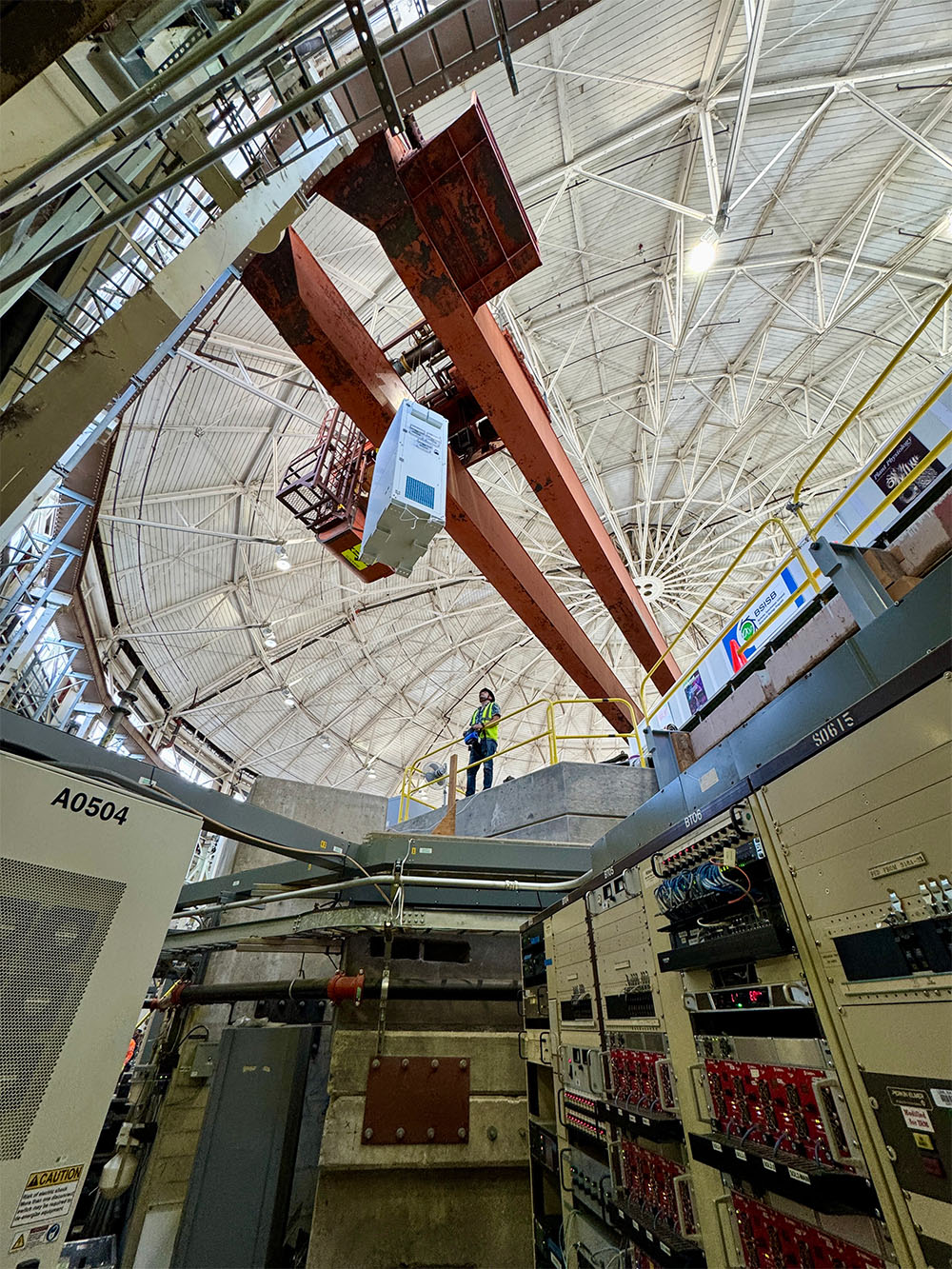 Person wearing safety gear helping to move large equipment inside the Advanced Light Source.