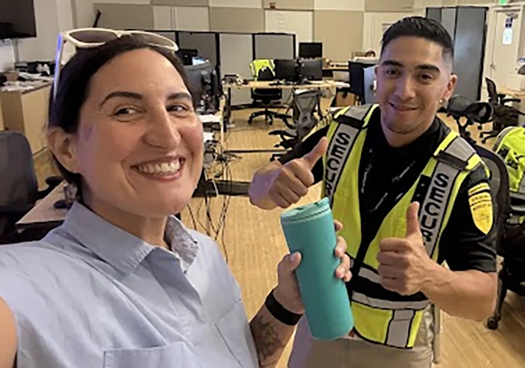 Smiling person with coffee mug and another person handing it to them