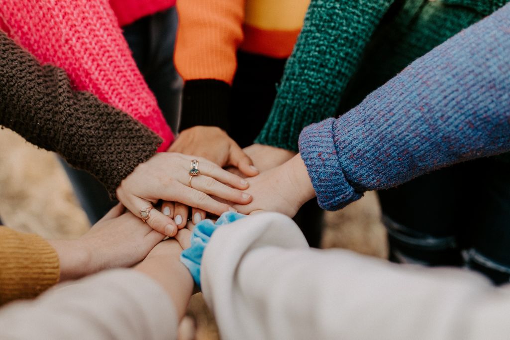 Closeup of hands of many persons laid on top of each other in show of unity.