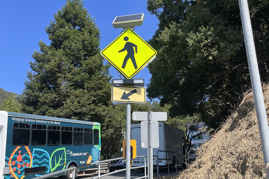 Yellow pedestrian crossing sign with bus in the background