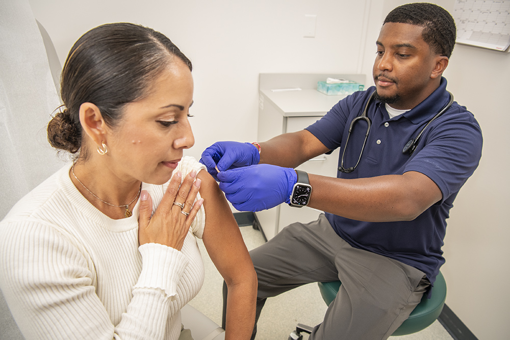 Health worker placing bandage on patient's upper arm