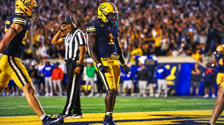 UC Berkeley football player wearing navy blue uniform and gold helmet celebrates in end zone with crowd in background.