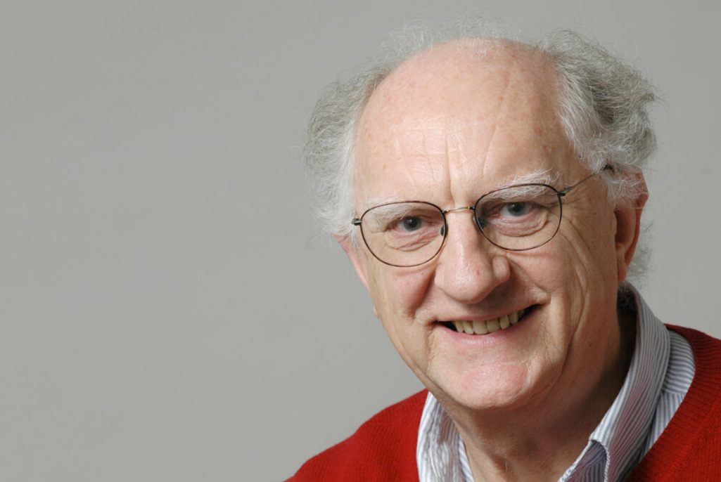 Person with white gray hair wearing glasses and red pullover sweater