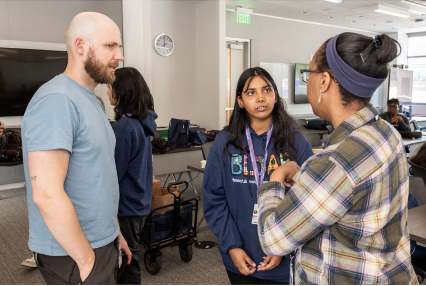 Three persons standing together in a meeting room talking to each other