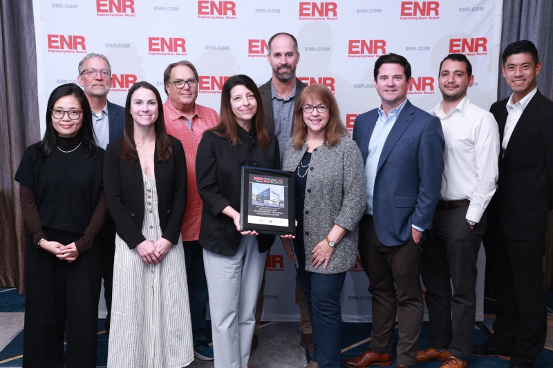 A group of people standing in front of a backdrop with the word "ENR" in red letters repeated across white background.