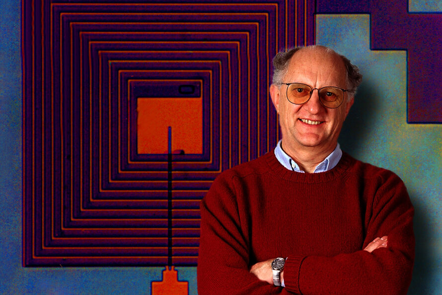 Person in dark red sweater wearing glasses standing in front of concentric square image on wall