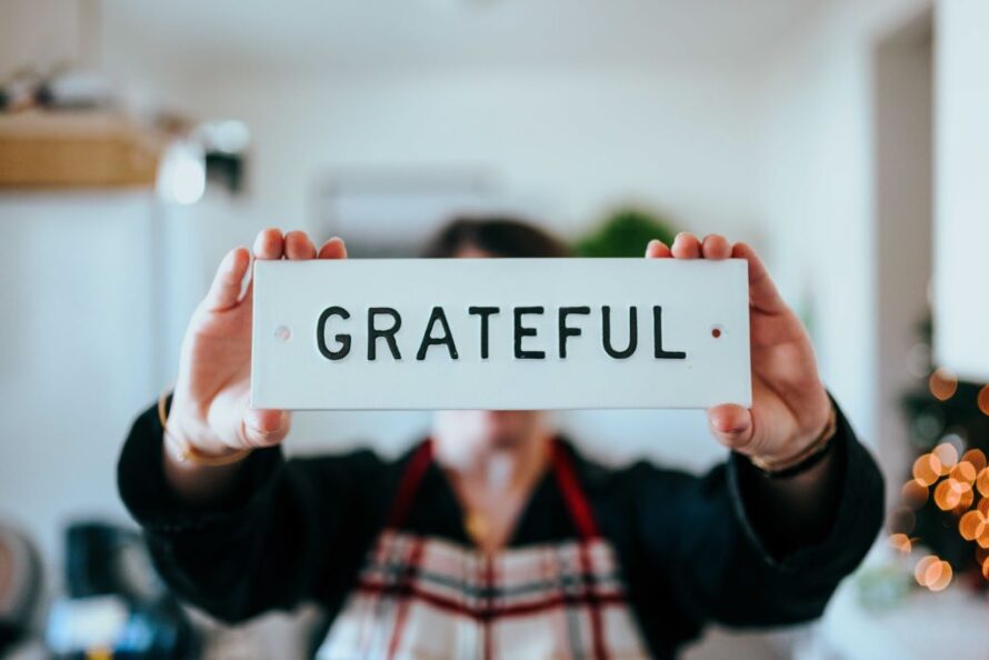 Closeup of blurred image of person holding in-focus placard reading "Grateful"