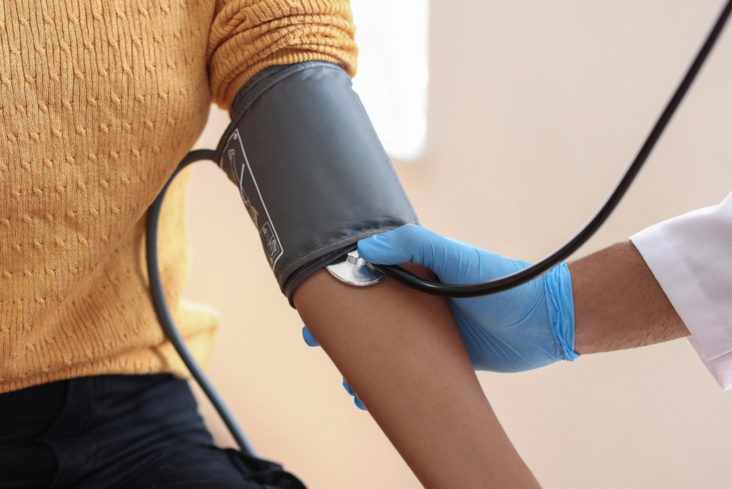 A medical professional measures a patient’s blood pressure.